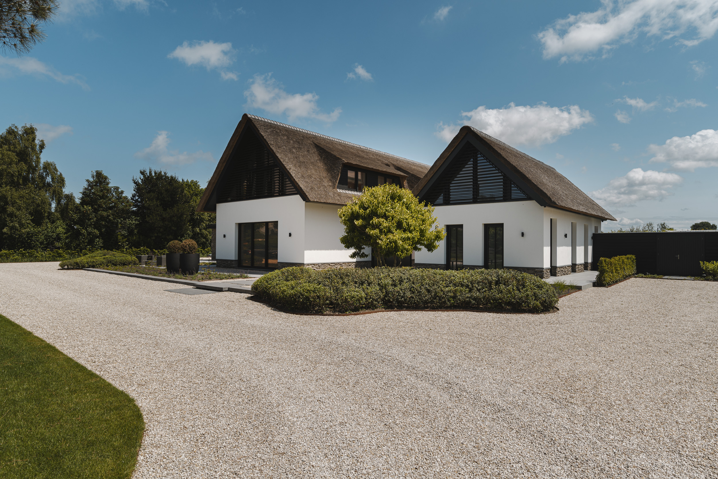 Witte villa met rieten kap en aangelegde tuin